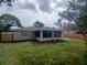 Backyard view of a home with dark window trim, a screened-in porch and green grass at 2414 Willow Oak Dr, Edgewater, FL 32141