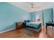 Cozy bedroom with blue walls, hardwood floors, bed with patterned blanket, and matching bedside table at 328 Fairfield Dr, Sanford, FL 32771