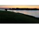 Picturesque water view at sunset, featuring a tranquil lake with a wooden dock and lush green landscape at 3774 Eagle Isle Cir, Kissimmee, FL 34746