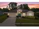 Charming single-story home with a well-manicured lawn, colorful flower beds, and a two-car garage at sunset at 813 Lancer Cir, Ocoee, FL 34761