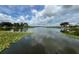 Expansive lake view reflecting the sky, surrounded by lily pads and verdant foliage, offering a serene waterfront setting at 813 Lancer Cir, Ocoee, FL 34761