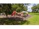Community playground with colorful play equipment, surrounded by a secure fence and grassy area at 9517 San Fernando Ct, Howey In The Hills, FL 34737