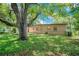 Spacious backyard with lush green grass and a large shade tree overhanging the home at 102 Mayrose Dr, Sanford, FL 32771