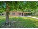 A cozy single-story house with a covered carport and lawn, partially shaded by a mature tree at 102 Mayrose Dr, Sanford, FL 32771