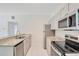 Updated kitchen features gray cabinets, stainless steel appliances, granite countertops, and tile flooring at 102 Mayrose Dr, Sanford, FL 32771
