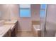 Bright bathroom featuring dual sinks, bathtub with tile surround, and a glass-enclosed shower at 12630 Old Plantation Ln, Orlando, FL 32824