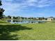 Scenic view of a pond surrounded by lush green grass and various houses in the background at 12630 Old Plantation Ln, Orlando, FL 32824