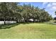 Large grassy backyard shaded by mature trees and surrounded by a white fence and black metal fencing at 13943 Caywood Pond Dr, Windermere, FL 34786