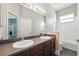 Double sink bathroom features modern sinks, vanity and mirror, with tiled bath and shower at 13943 Caywood Pond Dr, Windermere, FL 34786