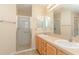 Bright bathroom with double sinks, vanity, mirrors, and a glass enclosed shower at 1425 Hollyberry Pl, The Villages, FL 32162