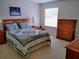 Comfortable bedroom with a wooden bed frame, soft carpet, and bright natural light at 1425 Hollyberry Pl, The Villages, FL 32162