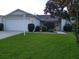 Charming one-story home with a well-manicured lawn, mature tree, and attached garage at 1425 Hollyberry Pl, The Villages, FL 32162