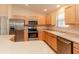 Well-equipped kitchen features stainless appliances, natural wood cabinets, and a breakfast bar at 1425 Hollyberry Pl, The Villages, FL 32162