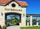 Elegant stone entryway with a decorative archway and beautiful landscaping, creating a grand sense of arrival at 15071 Guava Bay Dr, Winter Garden, FL 34787