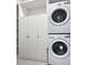 Modern laundry area with stacked washer and dryer, cabinets and shelving for organized convenience at 15071 Guava Bay Dr, Winter Garden, FL 34787