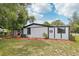 A white house with black trim, a well-maintained lawn, and mature trees casting shadows at 18015 Beach St, Umatilla, FL 32784