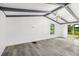 Bright living room featuring vaulted ceilings, wood beams, and stylish gray wood-look flooring at 18015 Beach St, Umatilla, FL 32784