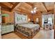 Cozy bedroom with wood walls, featuring a bed with floral comforter, a desk, and green dressers at 187 N Samsula Dr, New Smyrna Beach, FL 32168