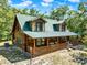 Inviting log cabin with a full-length porch and a green metal roof at 187 N Samsula Dr, New Smyrna Beach, FL 32168