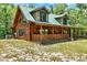 Charming log cabin with covered porch, surrounded by lush greenery and clear skies at 187 N Samsula Dr, New Smyrna Beach, FL 32168