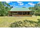 Exterior view of cabin featuring a green metal roof, screened porch, and large lawn at 187 N Samsula Dr, New Smyrna Beach, FL 32168