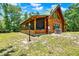 Charming log cabin featuring a green metal roof, screened porch, and spacious surrounding lawn at 187 N Samsula Dr, New Smyrna Beach, FL 32168