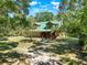 Charming log cabin home with a green metal roof and a covered porch surrounded by lush greenery at 187 N Samsula Dr, New Smyrna Beach, FL 32168