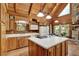 Cozy kitchen with wood cabinets, island cooktop, and view of the living area and stone fireplace at 187 N Samsula Dr, New Smyrna Beach, FL 32168