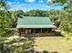 Charming log cabin with a green metal roof and a screened-in porch, blending into the natural surroundings at 187 N Samsula Dr, New Smyrna Beach, FL 32168