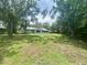 Spacious backyard featuring green lawn, mature trees and a light blue single story home at 3695 Dale Ct, Mount Dora, FL 32757