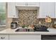 Close up of the kitchen sink, countertop, faucet, and colorful tiled backsplash at 419 Cierra Oaks Cir, Lady Lake, FL 32159