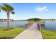A dock over the lake with homes in the background, palm trees, lush grass and a blue sky at 5065 Sparkling Water Way, Kissimmee, FL 34746