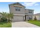 Two-story home showcasing a two-car garage, neutral-colored exterior, tidy landscaping, and a paved driveway at 5065 Sparkling Water Way, Kissimmee, FL 34746