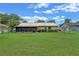 Charming home exterior showcasing a well-maintained lawn, screened-in patio, and vibrant flowering bushes at 708 Duffer Ln, Kissimmee, FL 34759