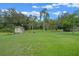 Expansive backyard featuring lush green grass, mature trees, and a charming storage shed at 708 Duffer Ln, Kissimmee, FL 34759