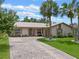 Charming single-story home featuring a beige exterior, metal roof, and a long brick driveway at 708 Duffer Ln, Kissimmee, FL 34759
