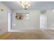 Living room featuring neutral walls, carpet floors, and an opening to the kitchen at 708 Duffer Ln, Kissimmee, FL 34759