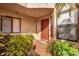 Inviting home entrance with a red front door, lush plants, and natural light at 7421 Sugar Bend Dr # 7421, Orlando, FL 32819