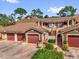 Condo featuring multiple units, red garage doors, and verdant green landscaping at 7421 Sugar Bend Dr # 7421, Orlando, FL 32819