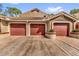 Exterior view of a home featuring a three car driveway and red garage doors at 7421 Sugar Bend Dr # 7421, Orlando, FL 32819