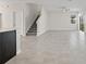 Open-concept living room boasts modern tile flooring and views into kitchen and stairs at 9069 Pinch Shot Dr, Winter Garden, FL 34787