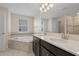 Luxurious bathroom featuring a soaking tub, dual vanities with quartz countertops, and tiled floors at 9069 Pinch Shot Dr, Winter Garden, FL 34787