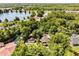 Aerial view of a home with a swimming pool surrounded by lush greenery and a lake at 9536 Peer Dr, Orlando, FL 32817