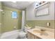 This bathroom features a vanity with sink, a toilet, and a tub/shower combo with green tiling at 9536 Peer Dr, Orlando, FL 32817