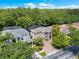 An aerial shot captures this lovely home with a brick drive and mature trees in a verdant neighborhood at 14244 Nottingham Way Cir, Orlando, FL 32828