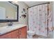 Bright bathroom with flamingo shower curtain, wooden vanity, granite countertop, and light tile floors at 14244 Nottingham Way Cir, Orlando, FL 32828