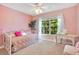 Cozy pink bedroom featuring a large window, light carpet, and decorative furnishings creating a warm, inviting space at 14244 Nottingham Way Cir, Orlando, FL 32828