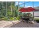 This screened patio features brick pavers, tropical landscaping, and outdoor seating with a shade umbrella at 14244 Nottingham Way Cir, Orlando, FL 32828