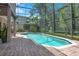 Inviting screened-in pool with a spa, surrounded by brick pavers and lush landscaping at 14244 Nottingham Way Cir, Orlando, FL 32828