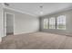 An empty bedroom with carpeting and neutral paint features plenty of natural light from the three windows at 14342 Fieldstone Lake Way, Orlando, FL 32824